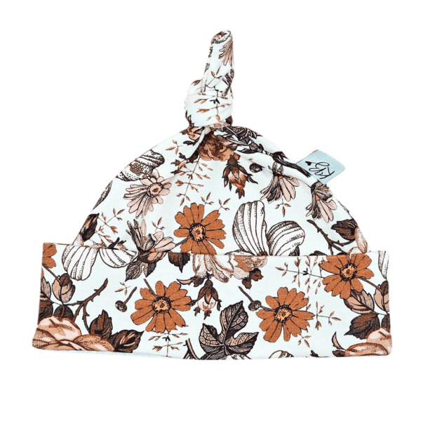 Babymuts met knoop bedrukt met oranje en bruine bloemen op witte achtergrond