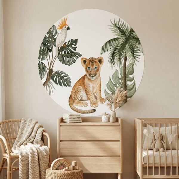 Ronde muurschildering met leeuwenwelpje, kaketoe en tropische bladeren in babykamer met houten meubels