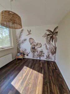 Kinderkamer met rieten hanglamp en bruintinten muurschildering van Afrikaanse dieren en tropische planten