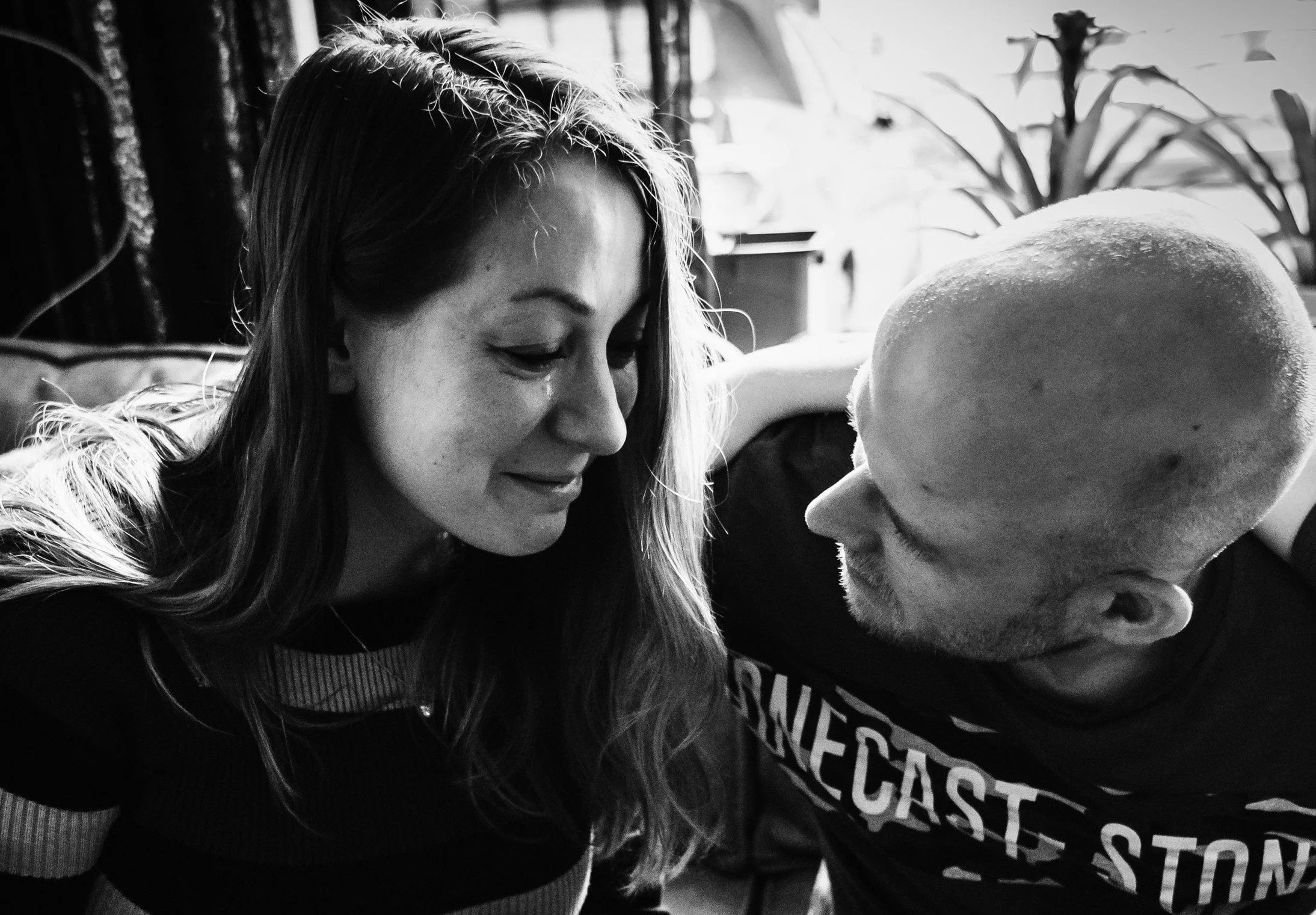 Stel kijkt elkaar liefdevol aan in zwart-wit portret met kamerplanten op achtergrond