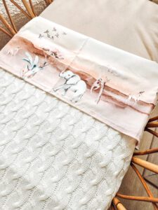 Babydeken met aquarel illustratie van konijntje en vogels in zachte pastelkleuren op rotan wiegje