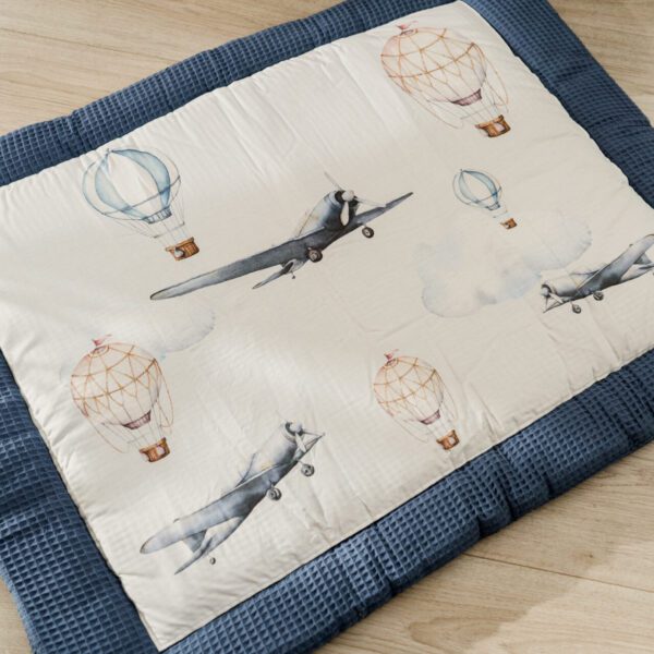 Speelkleed voor baby's met blauwe rand en vintage vliegtuigen en luchtballonnen patroon op houten vloer
