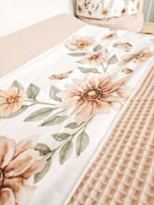 Waffeldeken met aquarel bloemenprint in zachte beige en groene tinten op bed met bijpassend kussen