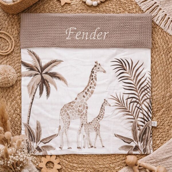 Gepersonaliseerde babydeken met giraffenprint en palmbladeren op natuurlijk gevlochten kleed met houten speelgoed