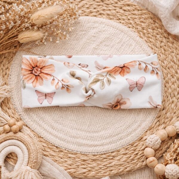 Witte haarband met bloemenprint en vlinders op rieten placemat met gedroogde bloemen en bohemian decoratie